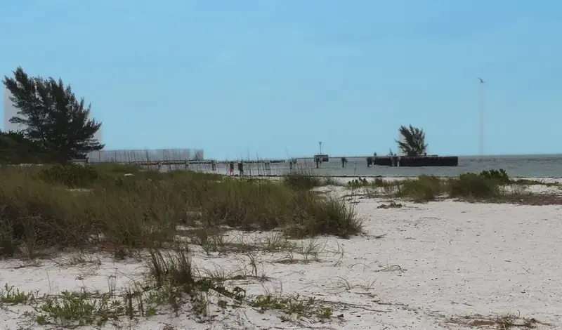 Gulf beach and a short pier under a blue sky (color edited)