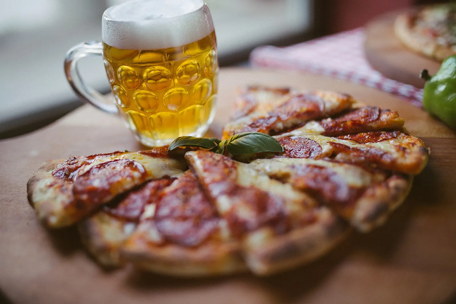 Beer and pizza on display in a restaurant on a rustic table with focus on the glass of beer