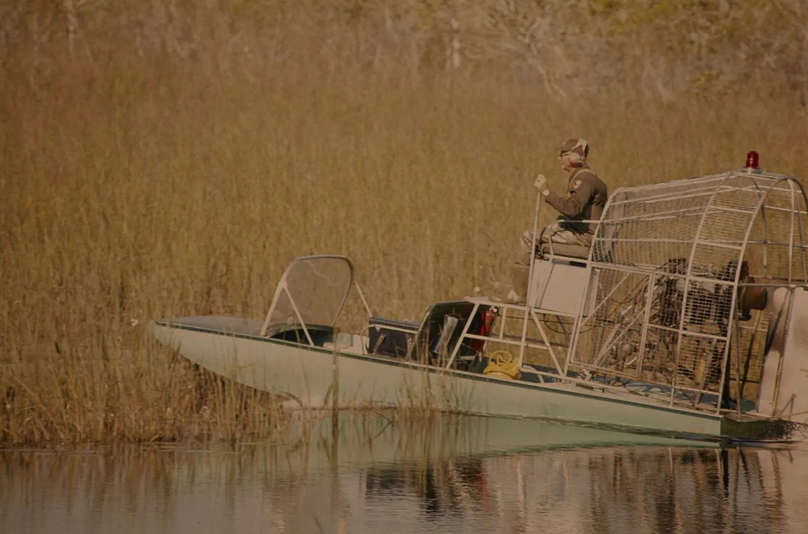 NPS employee riding in an airboat in Everglades National Park. Keywords: nps staff; boat; plant; river; NPS Personnel; (NPS History Collection Themes); Flora; Transportation